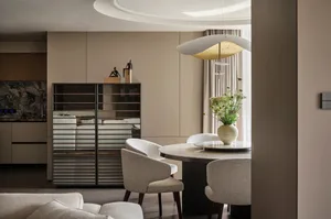 A modern dining room with a transparent lighting fixture, round table, and upholstered chairs.