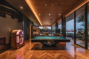 Well-lit, modern game room featuring a pool table, jukebox, and comfortable seating.