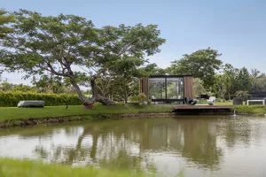 Modern house with glass walls and wood accents on waterfront property.