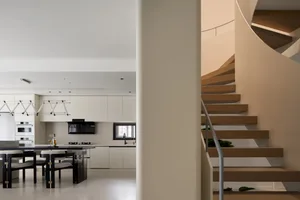 Minimalist modern kitchen and staircase intersection featuring wood stairs with concrete walls and floor.