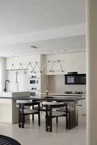 Modern kitchen featuring white cabinets, black furniture, and marble floor.