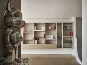 A modern living room featuring wooden shelves with books, vases, and decorative items.