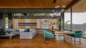 A modern living room featuring a gray sectional sofa and green armchairs, set against a backdrop of wooden paneling and a lar