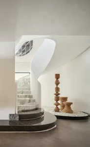 A modern staircase made of marble with a geometric wooden sculpture beside it.