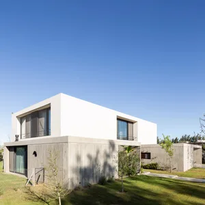 A modern, minimalist concrete house with large windows and a clean, simple design.