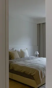 A modern bedroom with fabric bedding and minimalist decor.