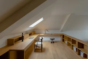A modern office with a wooden desk, lamp hanging from the ceiling, and a hanging light fixture.