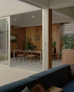 Modern residential dining room featuring wooden walls and glass doors.