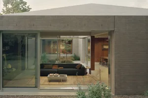 A modern residential interior with a minimalist design, featuring a concrete wall and floor, and a comfortable seating area w