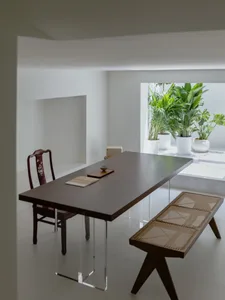 Modern minimalist dining room with a glass table and white walls.