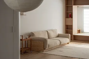 A minimalist living room with a sofa and a wooden cart.