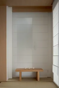 A minimalist tea ceremony setting featuring wooden furniture and three small cups on a wooden table.