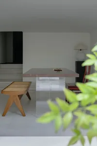 A modern glass table and wooden bench in a minimalist interior setting.