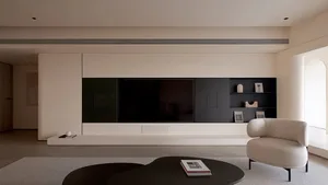 A modern living room featuring a concrete platform with a television unit, a single white armchair, and a black coffee table 