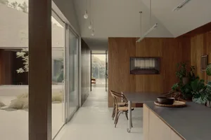 A modern living room with wooden floors, glass walls, and concrete surfaces.