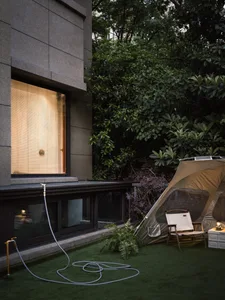 A minimalist outdoor area with a tent, chair, and garden setting.