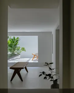 A modern minimalist studio apartment featuring a minimalist furniture arrangement, concrete floor, and green plants.