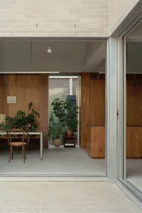 A modern residential living space with wooden walls, glass sliding doors, and concrete flooring.