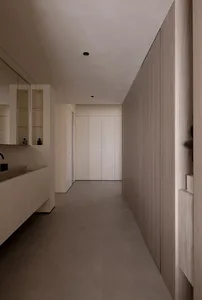 Modern, minimalist corridor featuring concrete tiles on the floor and white walls with a light wood finish.