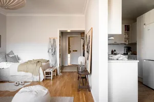 A minimalist residential space featuring white walls, wood flooring, and natural fiber textiles.