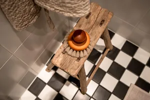 A minimalist wooden bench with a circular wooden base and a circular brush head made of white bristles.