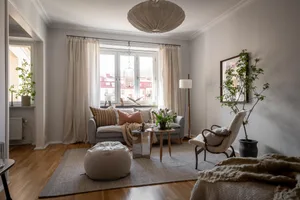A minimalist living room with a grey sofa, wooden coffee table, and large windows.