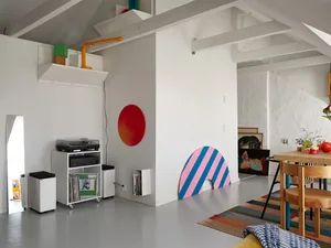 A minimalist living room featuring a white floor, white walls, and colorful striped geometry.