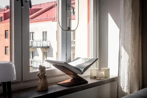 Minimalist living room featuring a wood-framed window with a book on a wooden stand.