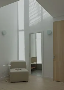 A minimalist living space with wooden panels, featuring a single chair and a small table.