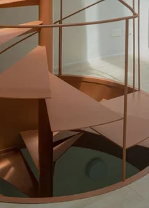A minimalist metallic staircase with circular steps and railings.