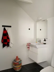 Modern minimalist bathroom with white ceramic tiles and floating vanity.