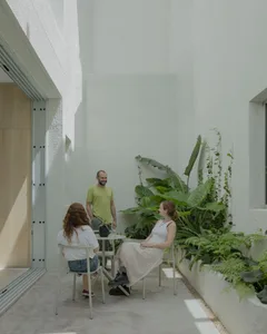 People enjoying a casual conversation in a modern garden setting with concrete planters and lush greenery.