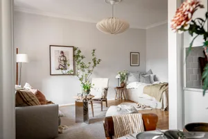 A modern living space with white walls, wooden floors, and fabric furniture, featuring a comfortable seating area, a cozy bed