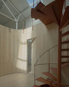 Modern, minimalist interior design featuring a wooden spiral staircase with metal railings.