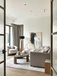 Modern living room with neutral-toned furniture, minimalist decor, and a large abstract painting.