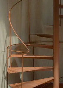 Modern metal spiral staircase with handrail inside a building.
