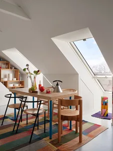 A modern minimalist kitchen featuring cork and wood materials with a skylight and colorful rug