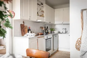 A modern residential kitchen featuring white tiles, stainless steel fixtures, and wood accents.