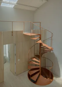 A modern, rotating staircase made of metal in a minimalist interior space.