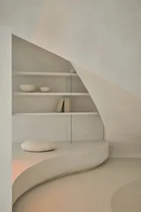 A minimalist living space featuring natural materials and a contemporary, curved seating area.