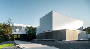Modern minimalist white cube house with concrete exterior, glass windows, and a minimalist garden.