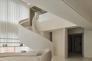 A modern interior design with a white concrete spiral staircase and minimalist decor.