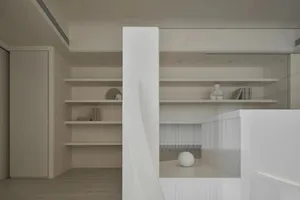 A minimalist interior space featuring modern wooden shelving with books and decorative items.