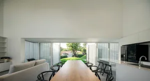 Modern residential space featuring sleek, minimalist design with wooden table, glass windows, and metal furniture.