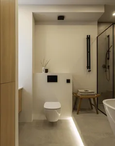 Modern minimalist bathroom with tiled walls, wooden accents, and metal fixtures