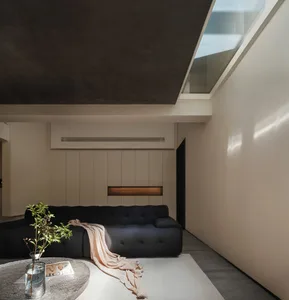 Minimalist living room featuring a concrete sofa and wooden paneling.