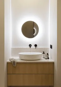 Modern bathroom with sink and marble counter, illuminated by ambient lighting.