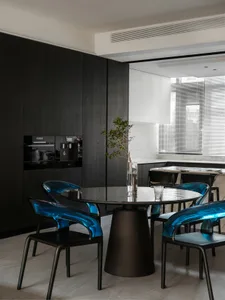 Modern kitchen with black wood cabinets, round glass table, and marble backsplash.
