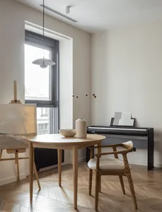 A modern home office featuring a wooden floor, table, chair, and piano.