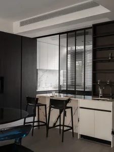 Modern kitchen with marble counter tops and black wood accents, featuring a breakfast bar.